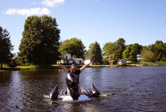 girl riding big loon floatie across northern ontario lake at the cottage