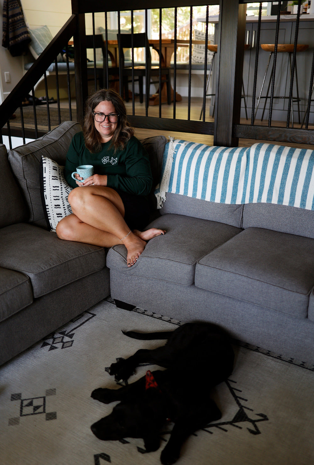 cabin  long sleeve tee on girl drinking kintore coffee at loon lake haus with black lab puppy on floor