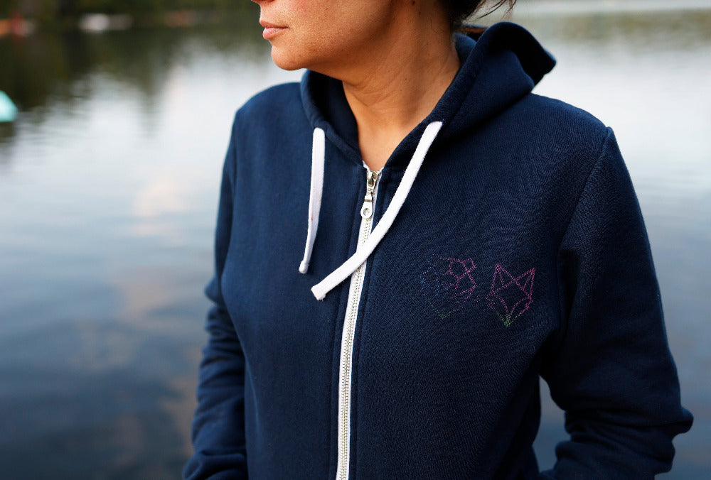 woman on dock wearing northern lights zip up hoodie in haliburton ontario