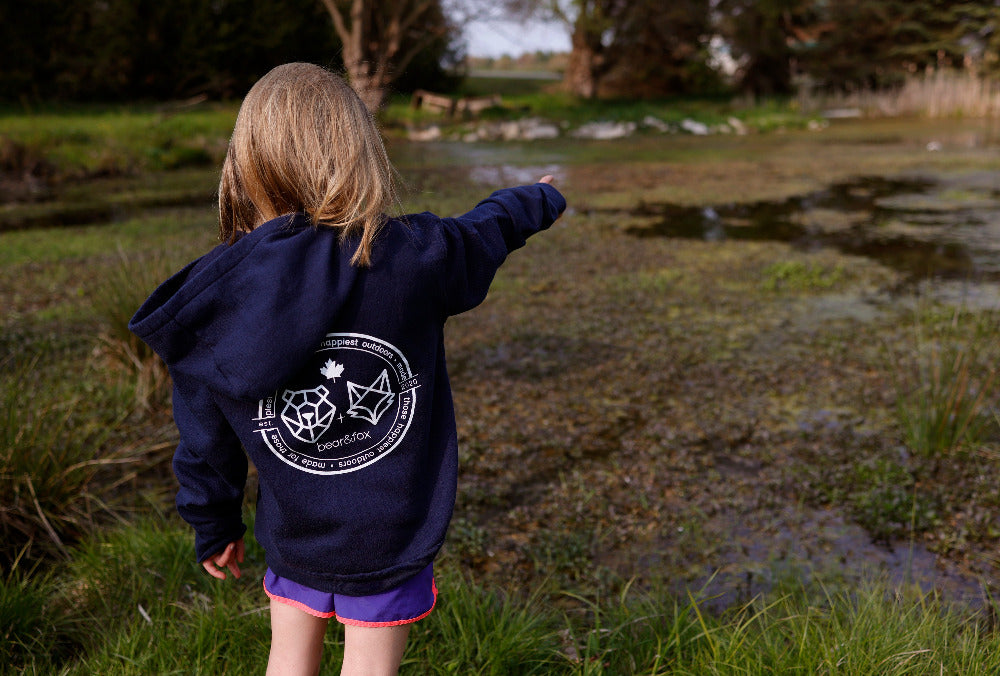 young girl in the cub hoodie pointing to a turtle in the pond